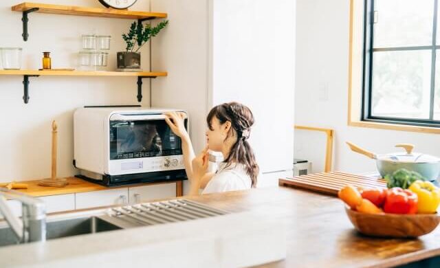 電子レンジの前で悩む人