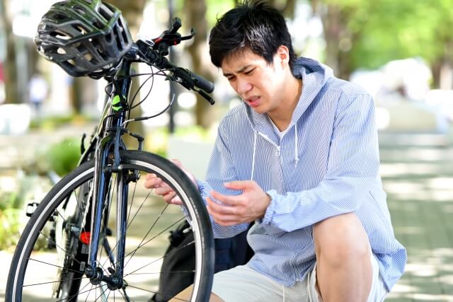 自転車のタイヤを見て困る男性